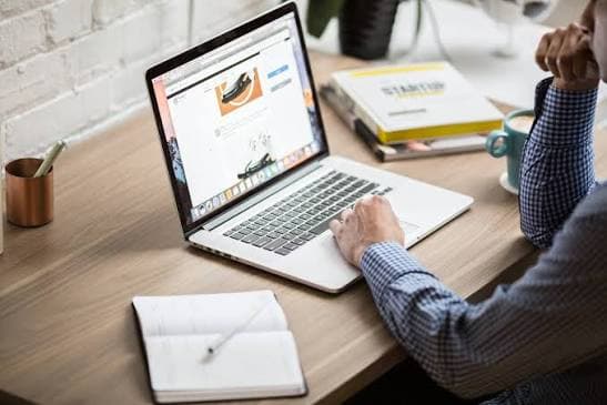 A professional working on a laptop at a wooden desk in a modern office